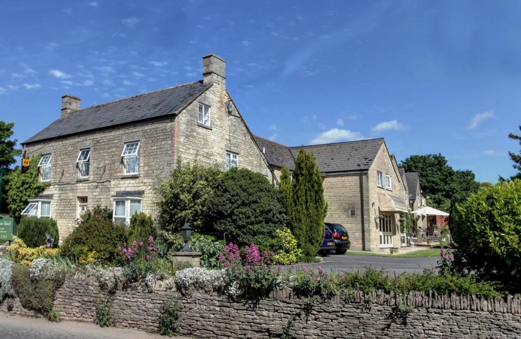 a large stone house with a stone wall at Pettifers Freehouse Hotel in Crudwell