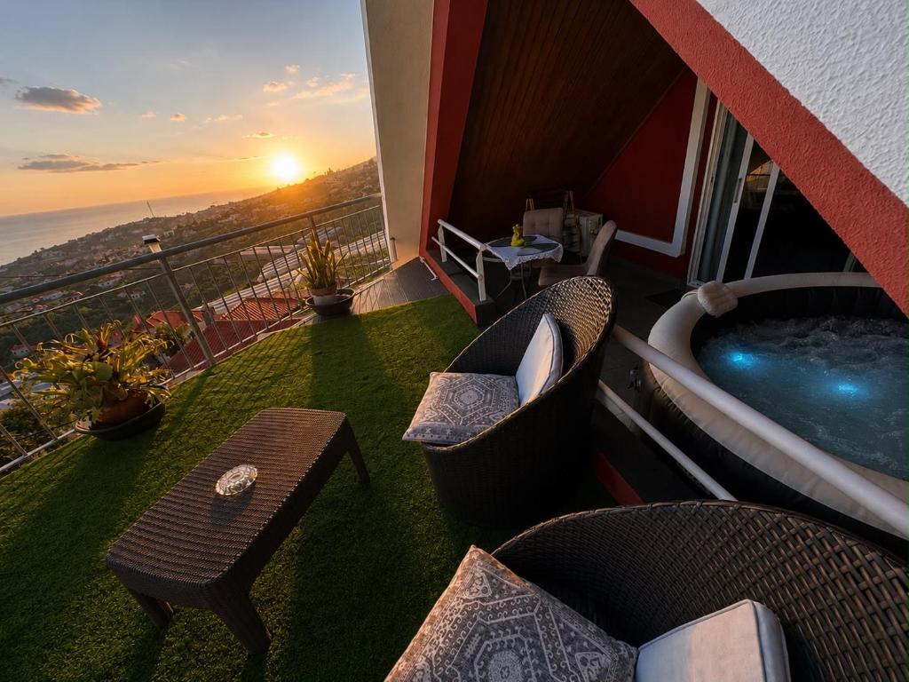 a balcony with a hot tub and chairs and a table at Studio privado com vista mar e montanha in Ponta do Sol