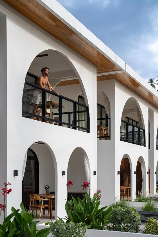 a man standing on the balcony of a house at Aqueduct resort in Ko Tao