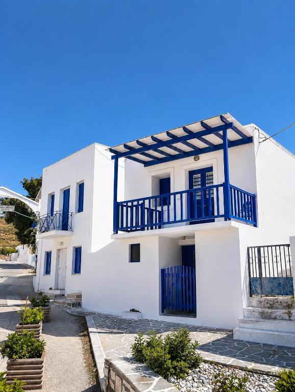 a white house with blue balconies on a street at Cozy apartments Paros Kostos in Kóstos