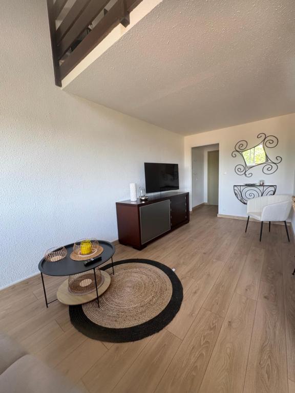a living room with a table and a television at Le recantou duplex in Marseillan