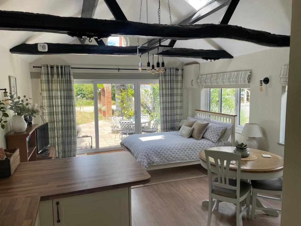 a bedroom with a bed and a table and a kitchen at Lavender Lodge in Briston