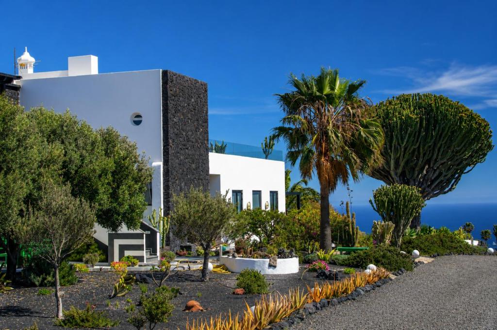 a white building with palm trees in front of it at 5 Suites Lanzarote in Mácher