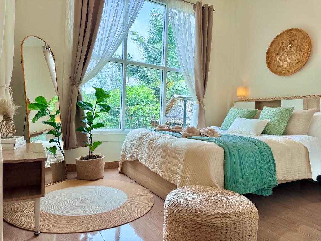 a bedroom with a bed and a large window at Chaloklum Beach House in Chaloklum