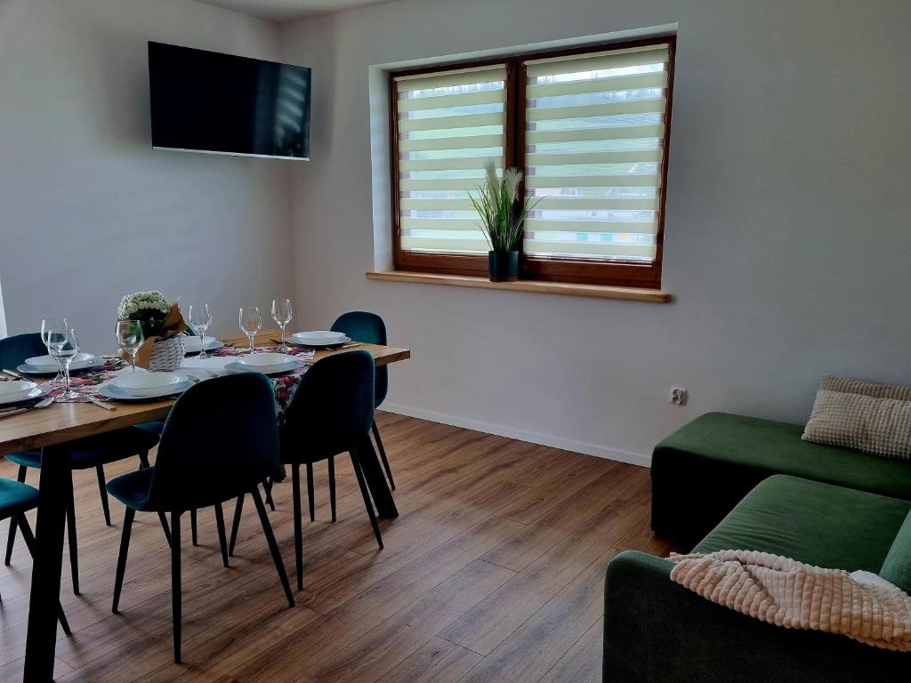 a dining room with a table and chairs and a couch at Zielony Zakontek in Ratułów