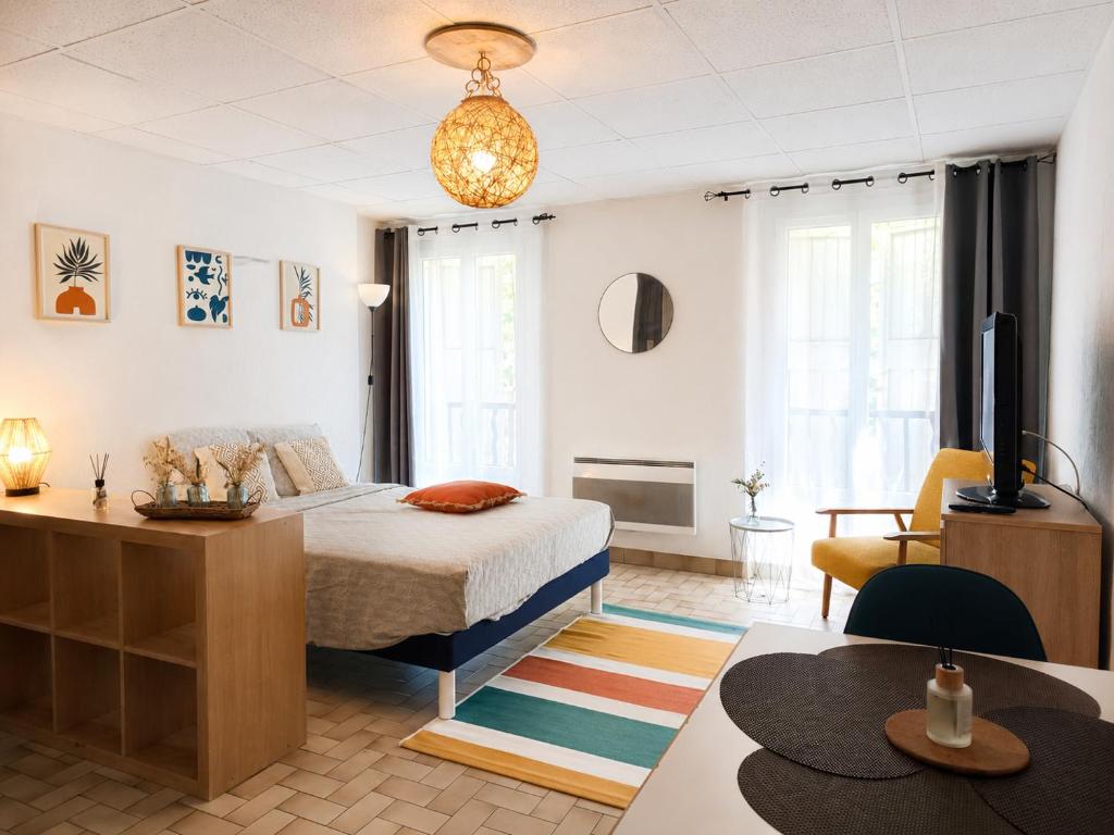 a bedroom with a bed and a desk and a television at Studio spacieux centre-ville avec ascenseur - Le Bohème in Digne-les-Bains