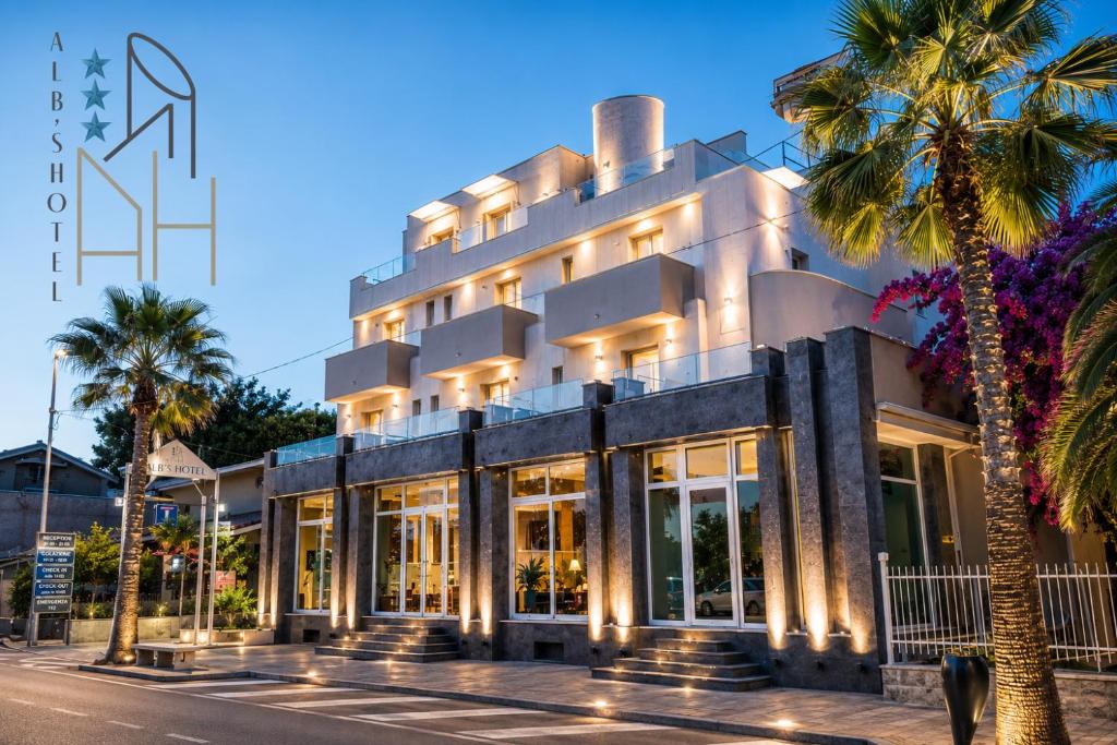a building with a palm tree in front of it at Hotel Alb's in Alba Adriatica