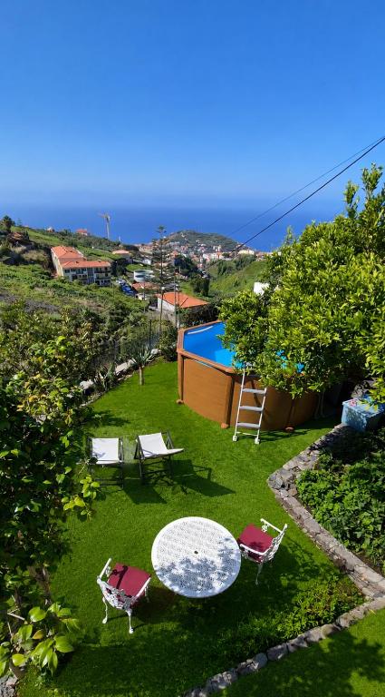 a garden with a table and chairs and a swimming pool at Quinta do Ribeiro Real in Câmara de Lobos