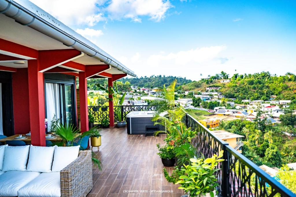 ein Balkon mit Sofa und Blick auf eine Stadt in der Unterkunft L'échappée verte Appart entier sans coupure d'eau in Mtsamgamouji