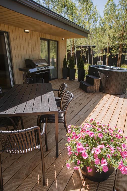 a wooden deck with a table and chairs and flowers at ForRest Glamp Saulkrasti in Saulkrasti