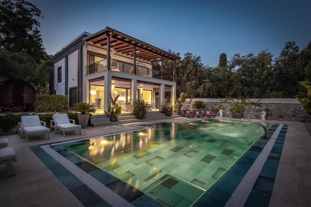 a house with a swimming pool in front of a house at Sea View Villa in most upscale Yalikavak in Bodrum City
