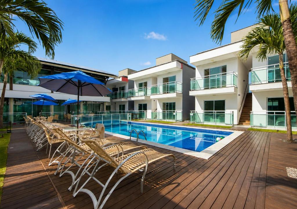 a pool with chairs and umbrellas next to a building at Pousada Oásis Tropical in Porto De Galinhas