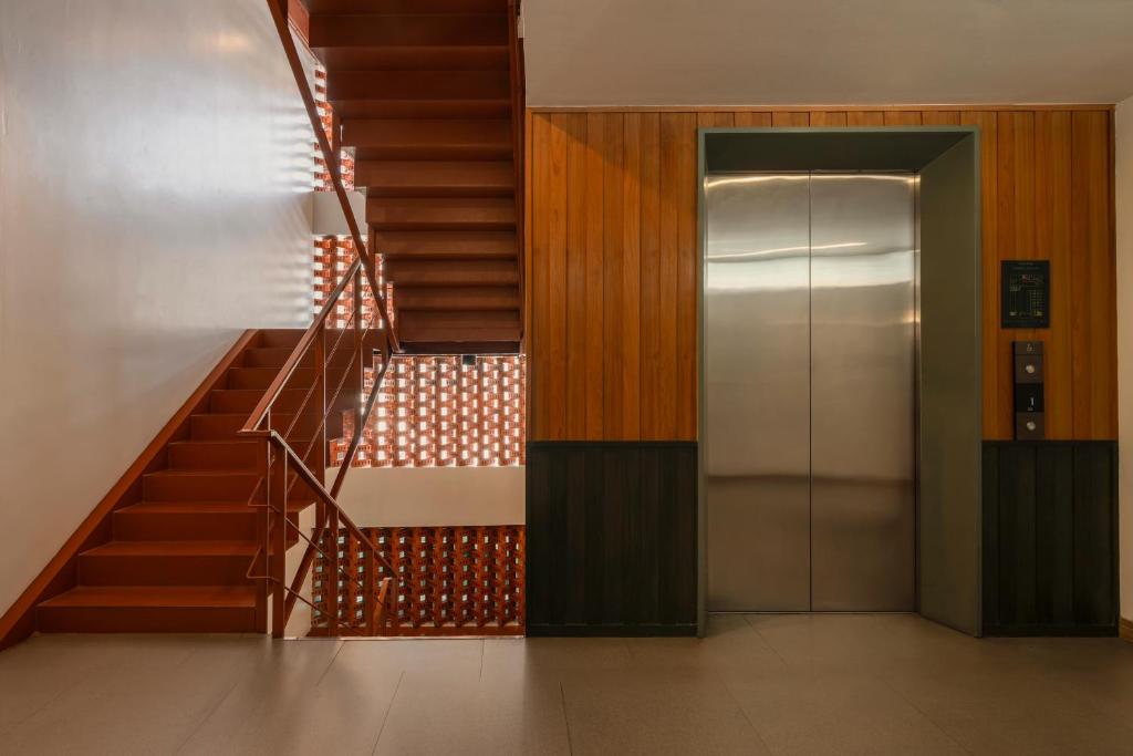 A wood-lined circulation area with a staircase, elevator and patterned screen wall.