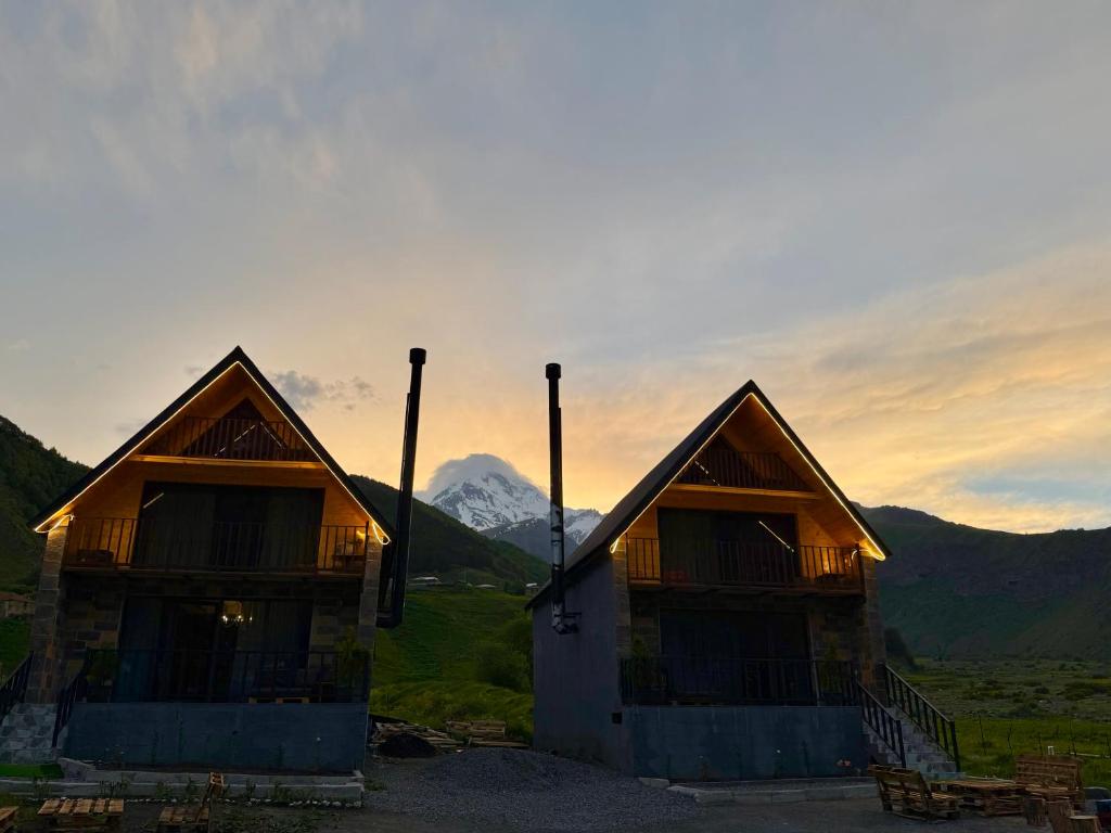 two wooden huts with a mountain in the background at Grand Hills Kazbegi in (( Gergeti ))