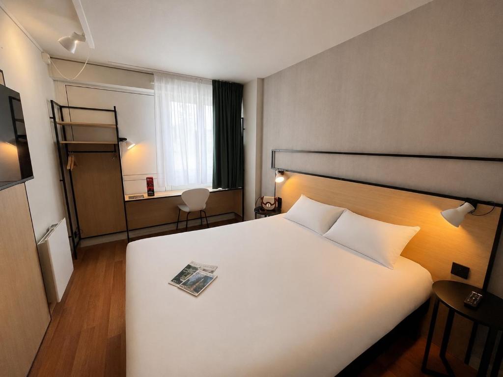 a hotel room with a bed with a magazine on it at ibis Alençon in Alençon
