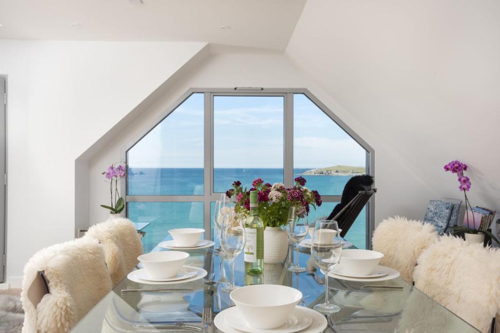 a glass table with white dishes and flowers on it at The Penthouse Fistral Beach, Newquay in Crantock