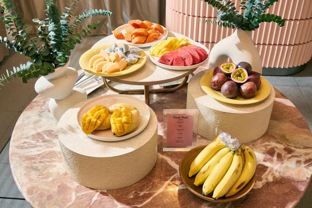 A fruit display featuring sliced melon, mango, dragon fruit, passion fruit, and bananas.