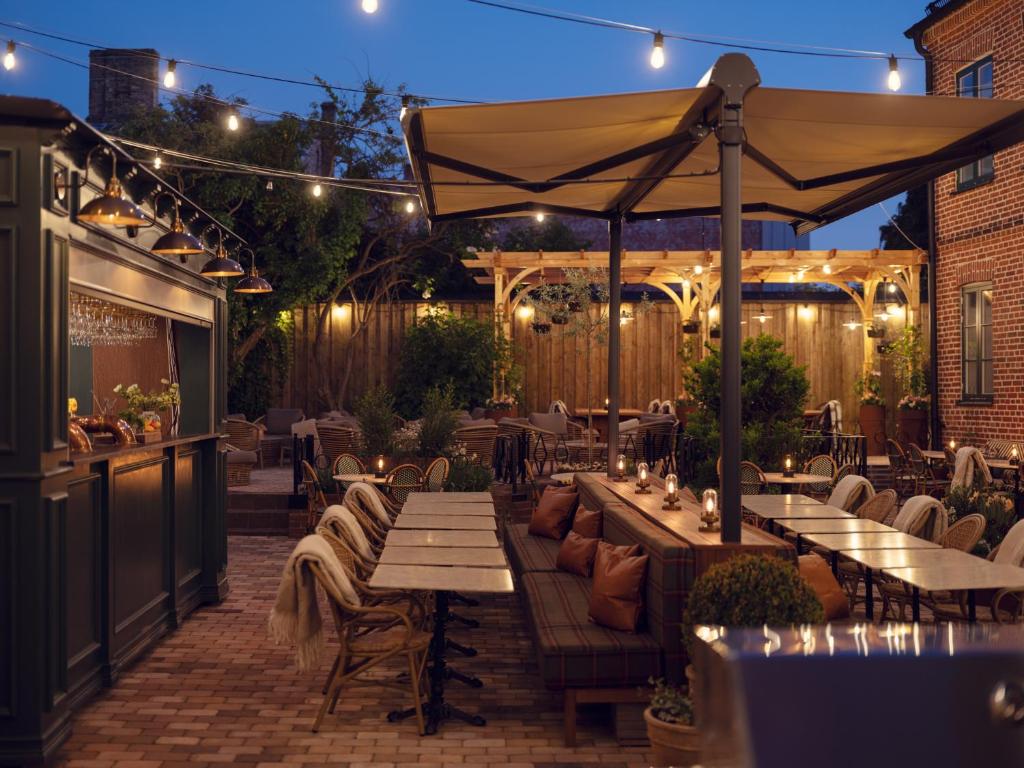an outdoor patio with tables and chairs and an umbrella at Hotel Bishops Arms Lund in Lund