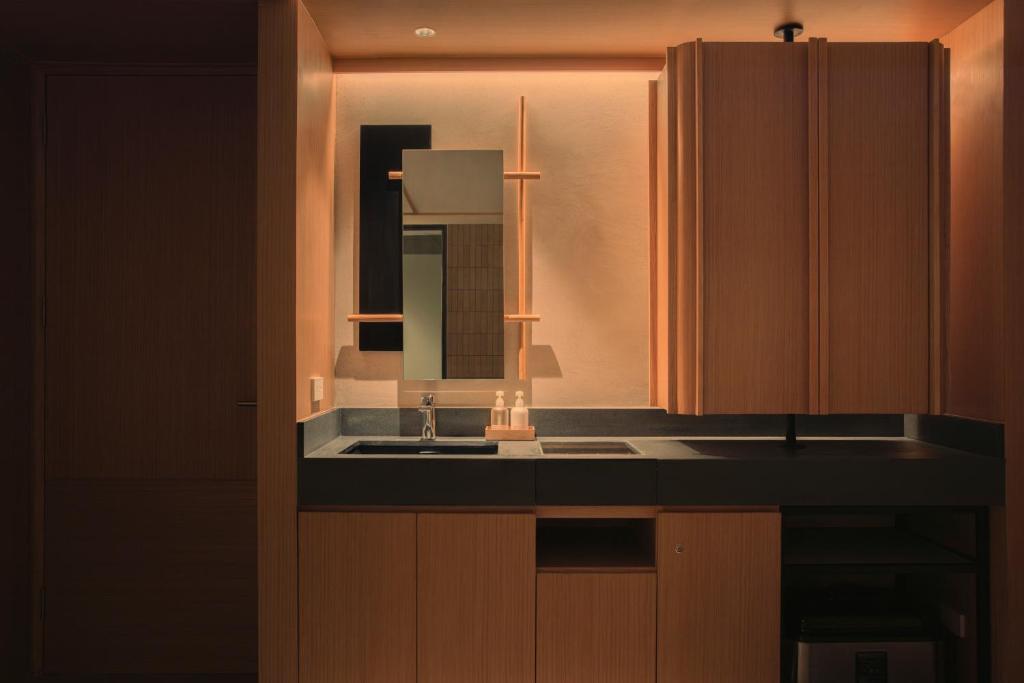A compact bathroom vanity with a sink, mirror, toiletries, and enclosed storage.