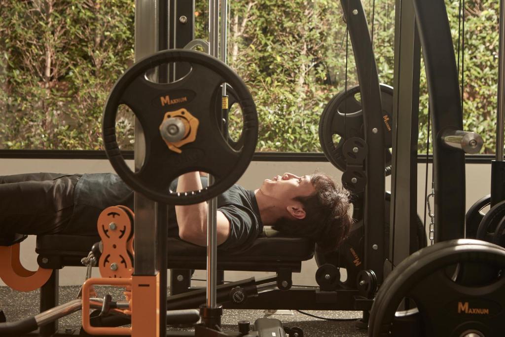 A strength-training scene beside windows, showing a loaded rack and bench.