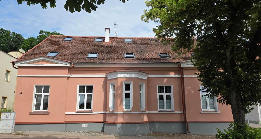 a pink house with a brown roof at Apartamenty MILANHOUSE in Gołdap