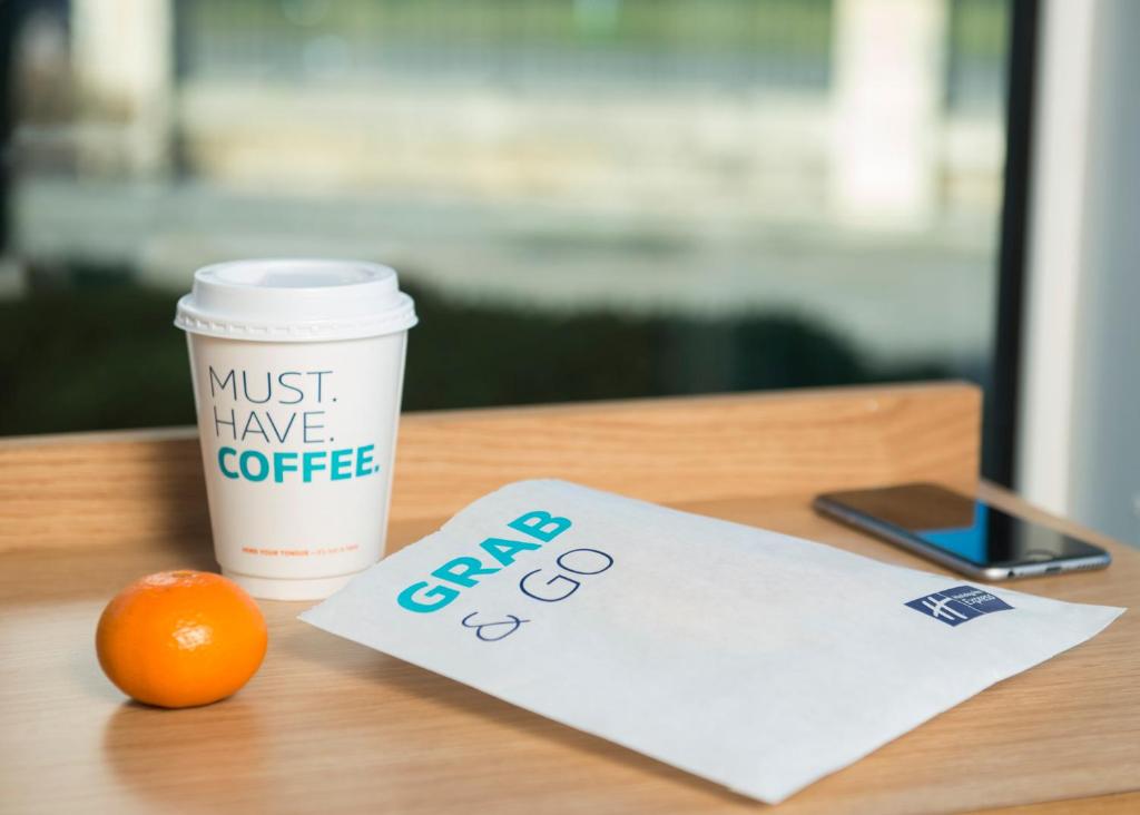 a cup of coffee and an orange on a table at Holiday Inn Express Stafford by IHG in Stafford