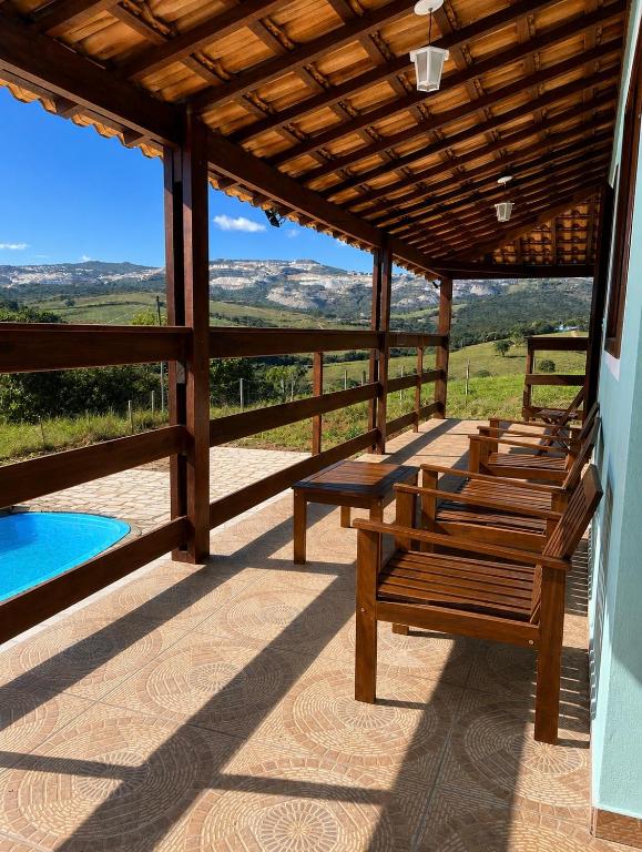 a group of benches sitting on a porch with a pool at Sítio Anna in São Thomé das Letras