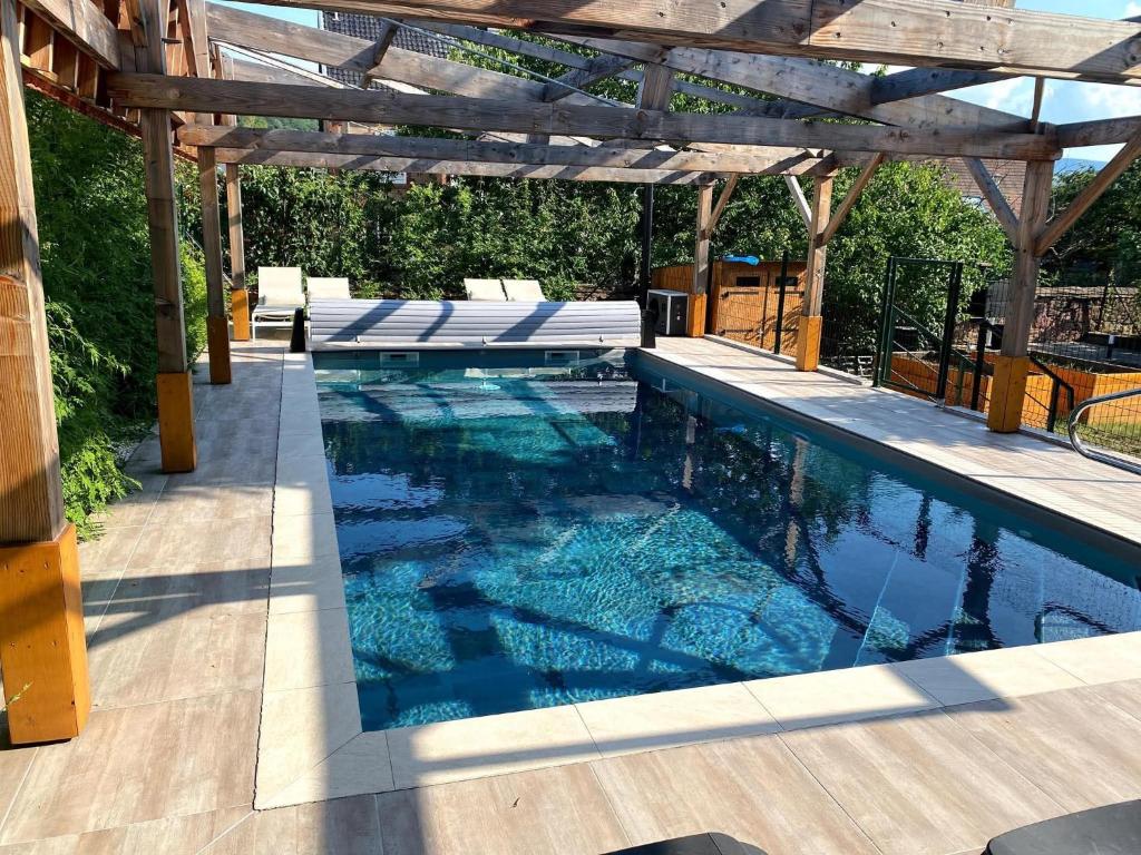 a swimming pool with a wooden pergola at Les Cigognes de Rosheim in Rosheim