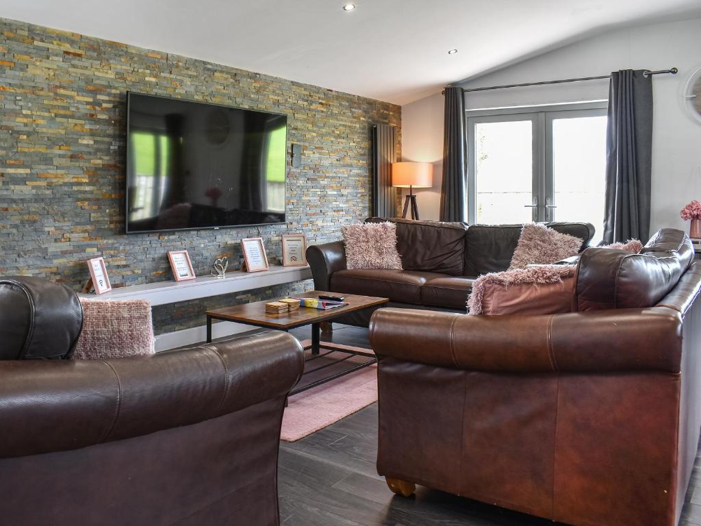 a living room with leather furniture and a brick wall at The Lune - Uk47035 in Kirkby Lonsdale