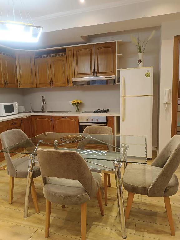 a kitchen with a glass table and chairs and a refrigerator at Arthouse Elbasan in Elbasan