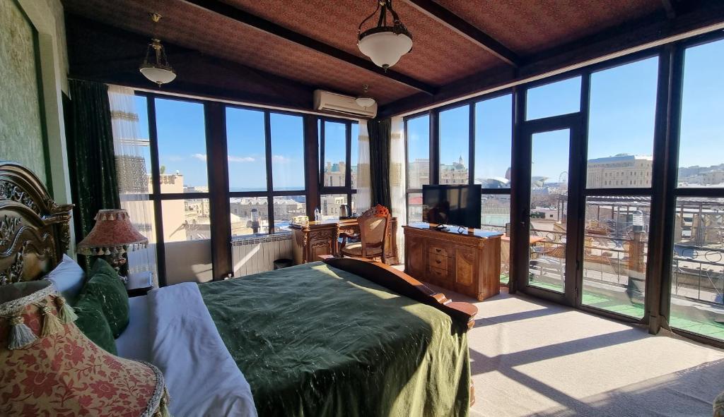 a bedroom with a bed and a tv and large windows at Grand Hotel 1902 in Baku
