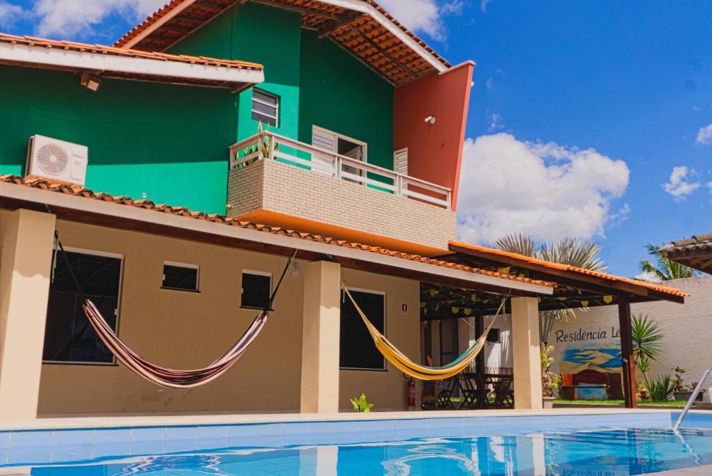 a house with hammocks in front of a swimming pool at Pousada Residência Lençóis in Barreirinhas