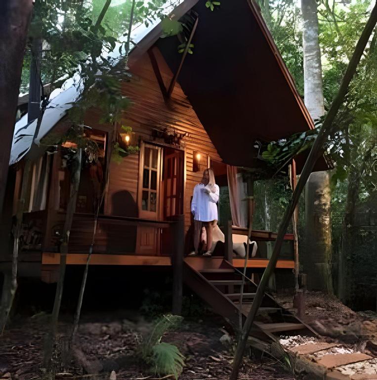 a woman standing on the porch of a tree house at Cabana Bem-te-vi in Três Coroas