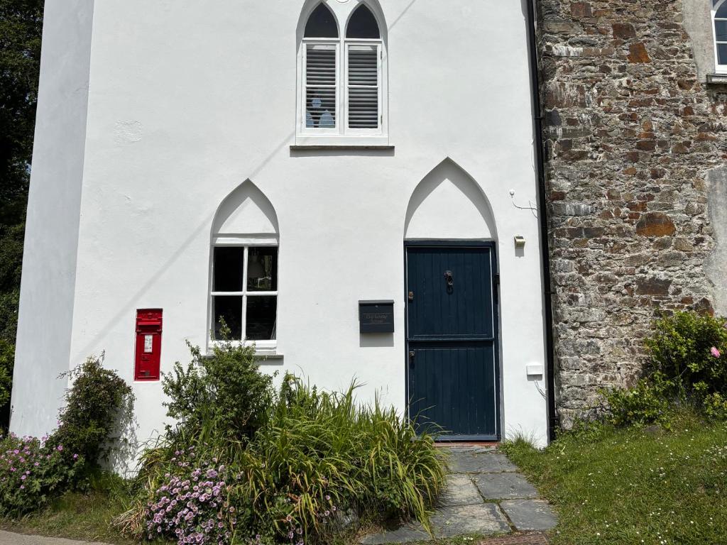 a white house with a blue door and two windows at Old Sunday School in Bideford