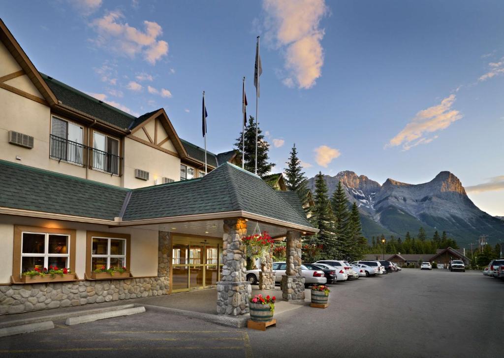 a hotel with cars parked in a parking lot with a mountain at Coast Canmore Hotel & Conference Centre in Canmore
