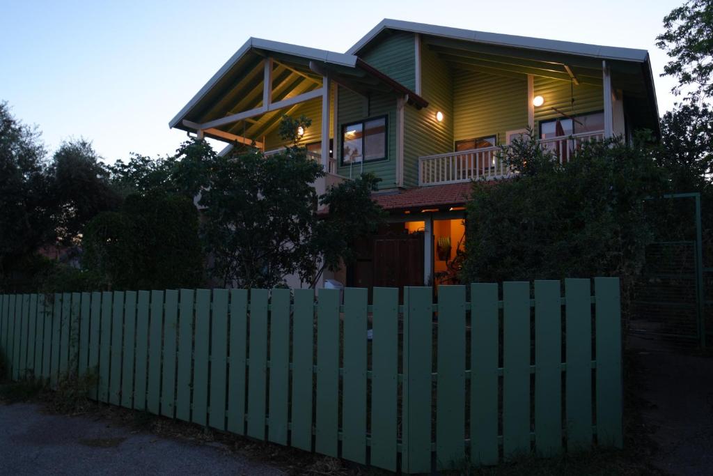 a green fence in front of a house at Aviv - Bakfar in Amirim in Amirim