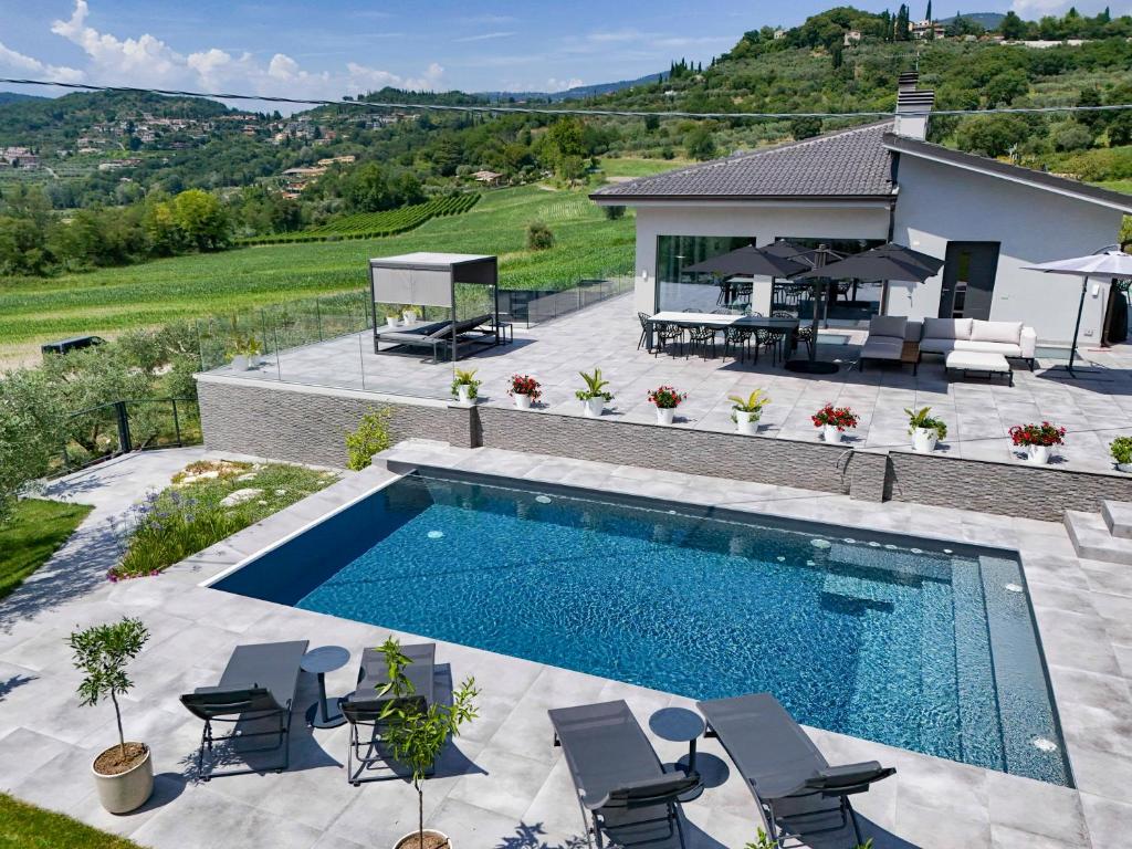 an image of a swimming pool with chairs and a house at Villa Casara Design and Relax Lago di Garda in Costermano