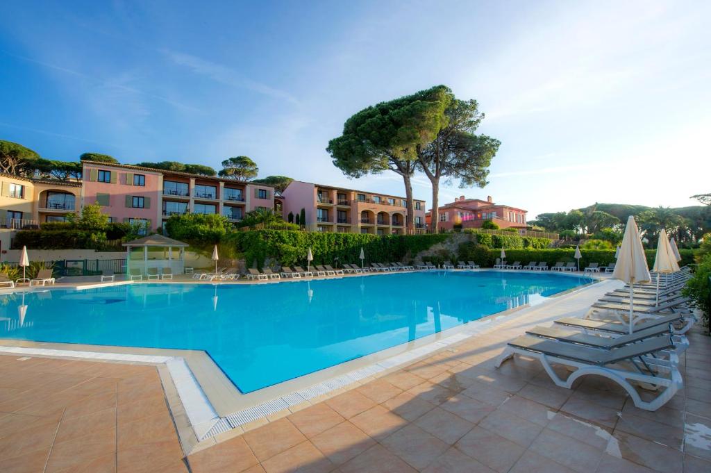 a large swimming pool with lounge chairs and condos at Hôtel Les Jardins De Sainte-Maxime in Sainte-Maxime