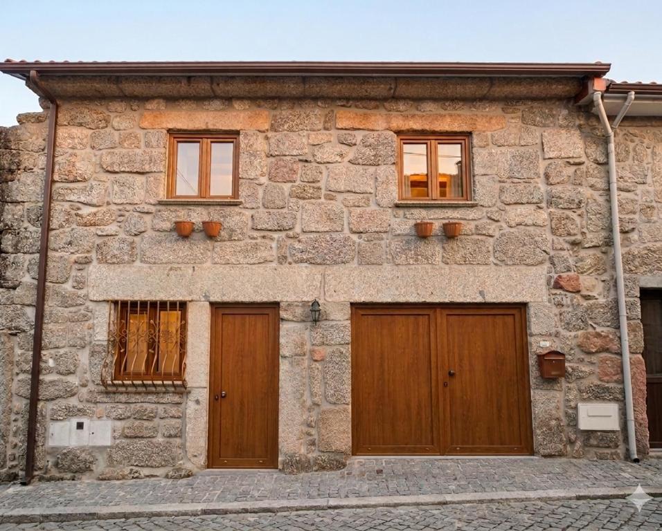 a stone building with two wooden doors and windows at Casa da Bia - Gerês in Terras de Bouro