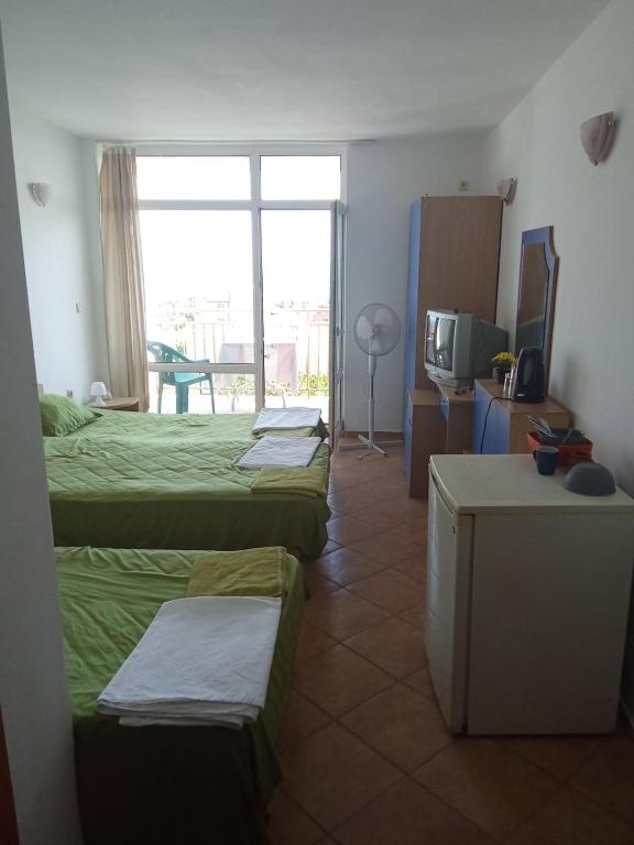 a hotel room with three beds and a television at Studio A in Sveti Vlas