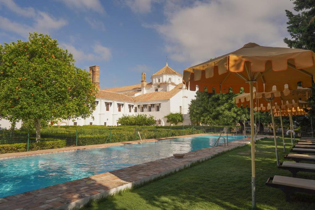 a swimming pool in front of a white house at Monasterio de San Francisco in Palma del Río