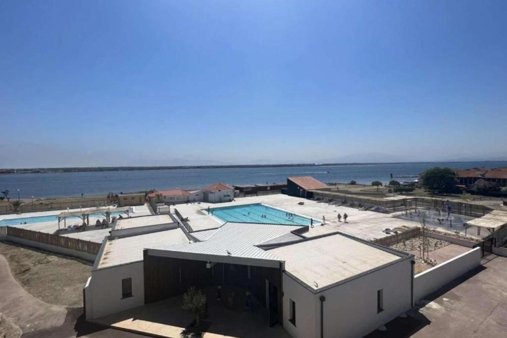 a building with a swimming pool next to the water at Beautiful cocoon with shared pool in Le Barcarès in Le Barcarès