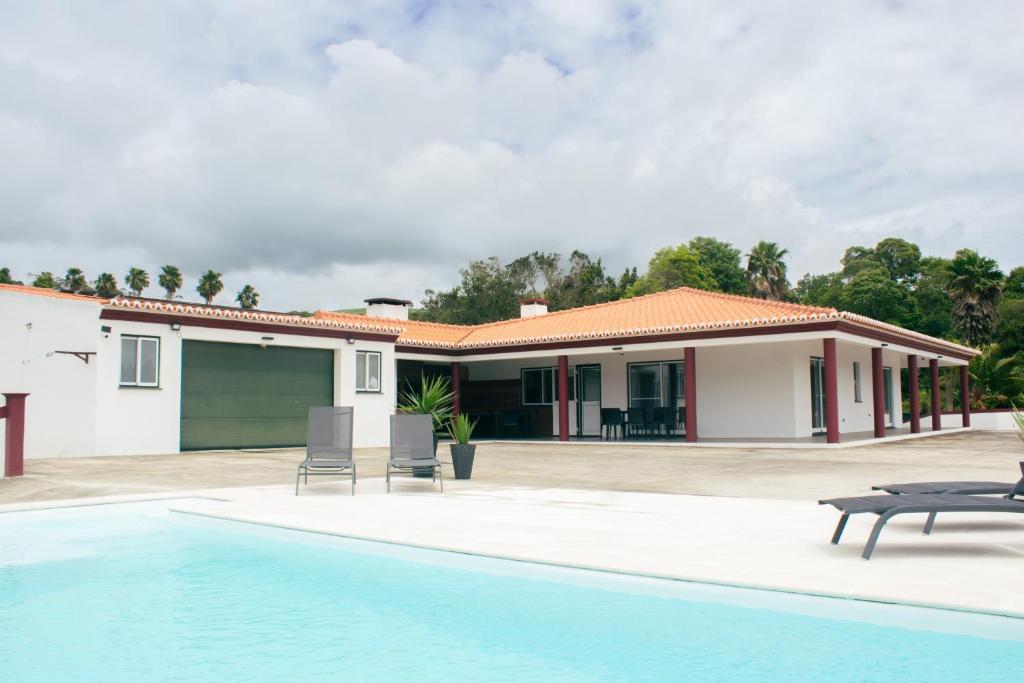 a villa with a swimming pool and a house at Chalé d'Angra Guest House in Angra do Heroísmo