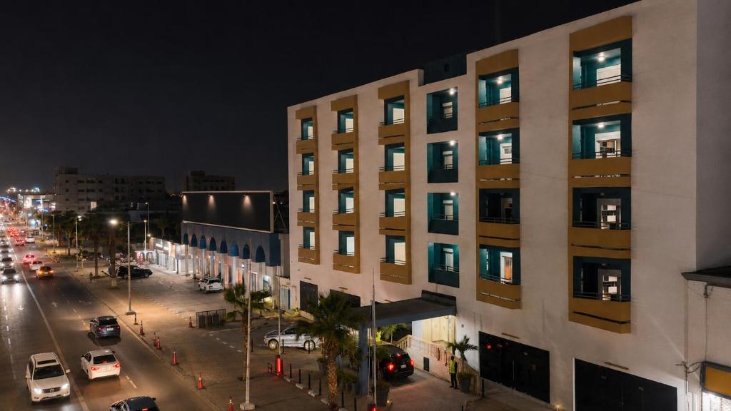 a tall white building with windows on a street at night at AB Business Hôtel in Nouakchott
