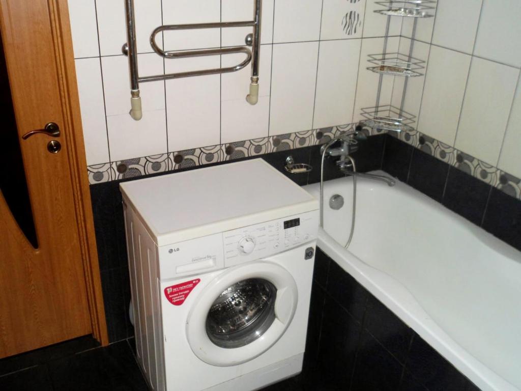 a washing machine in a bathroom next to a bath tub at Петропавловская 16 in Okhtyrka