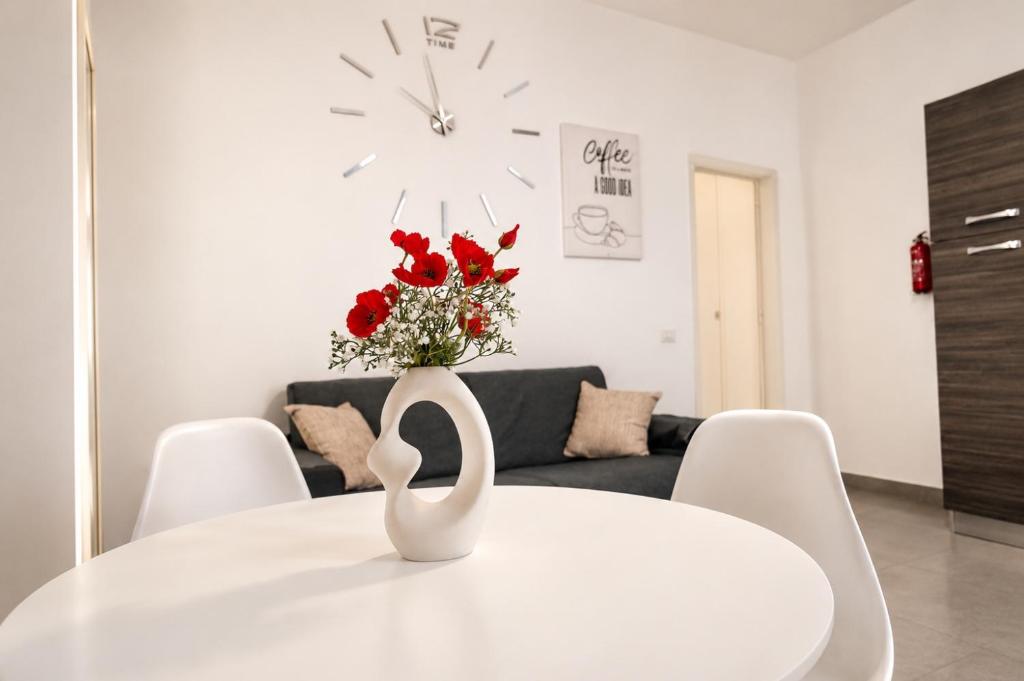 a white dining room table with a vase of red roses at Maison Alexeur - Intero Appartamento in Crotone