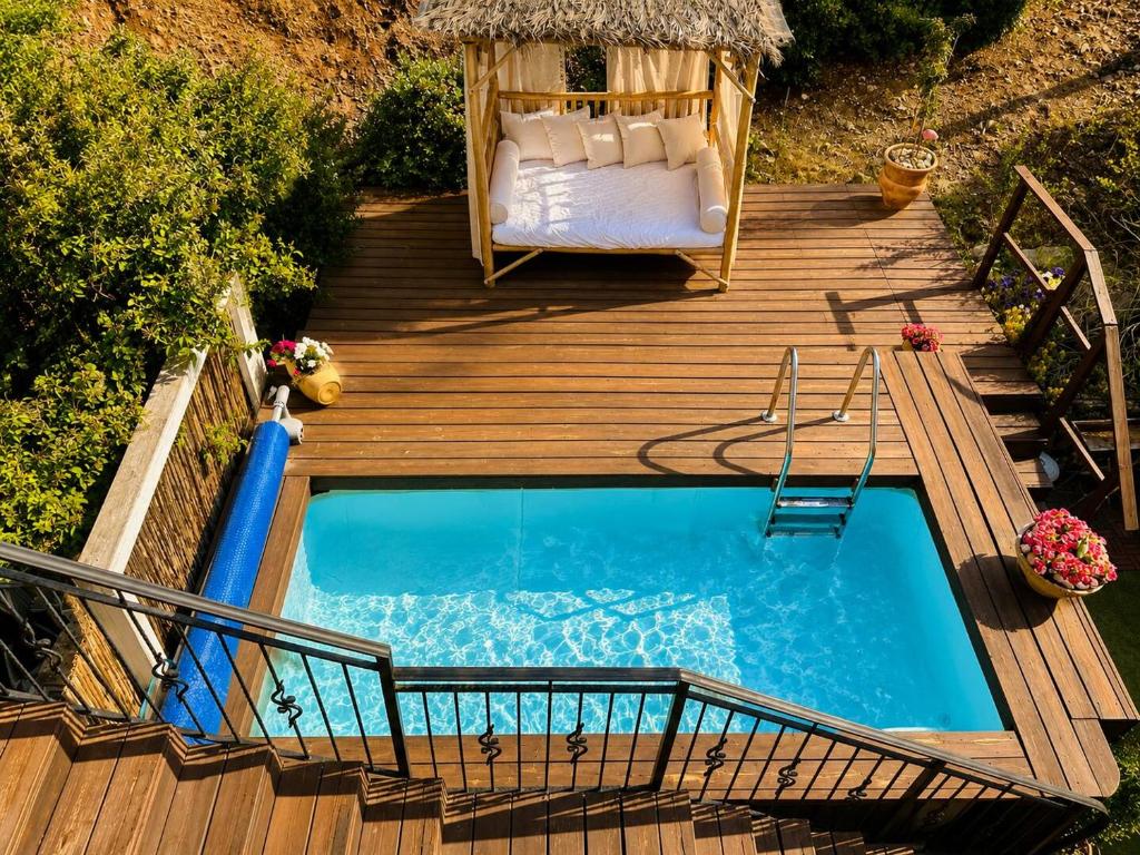 a wooden deck with a swimming pool with a bed and a table at זוג ידיים - סוויטה עם בריכה פרטית, סאונה וג'קוזי in H̱osen