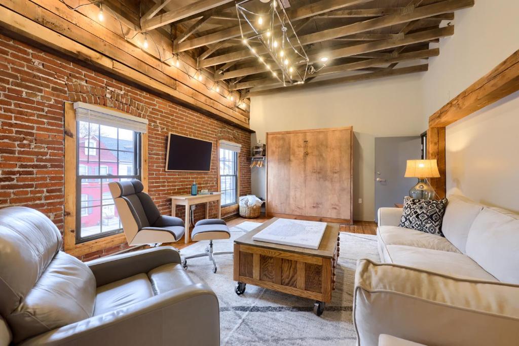 a living room with couches and a brick wall at Sweet Lancaster Apt. B in Lancaster