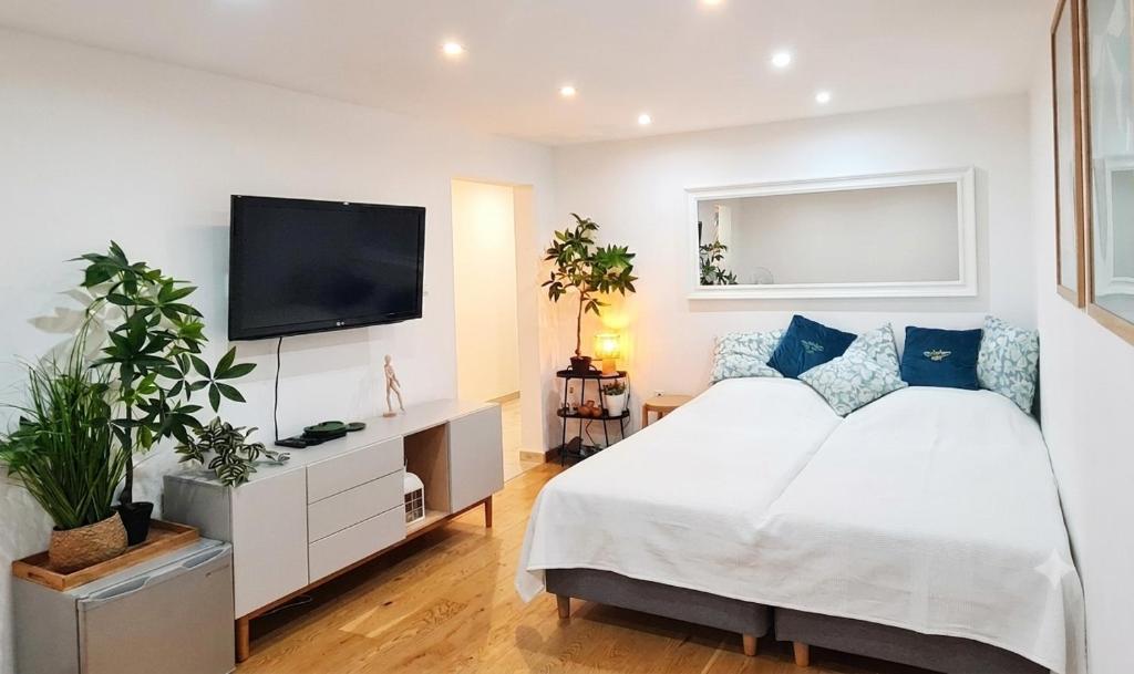 a white bedroom with a bed and a flat screen tv at Apartament Tęczowy Tukan -1 piętro in Kwidzyn