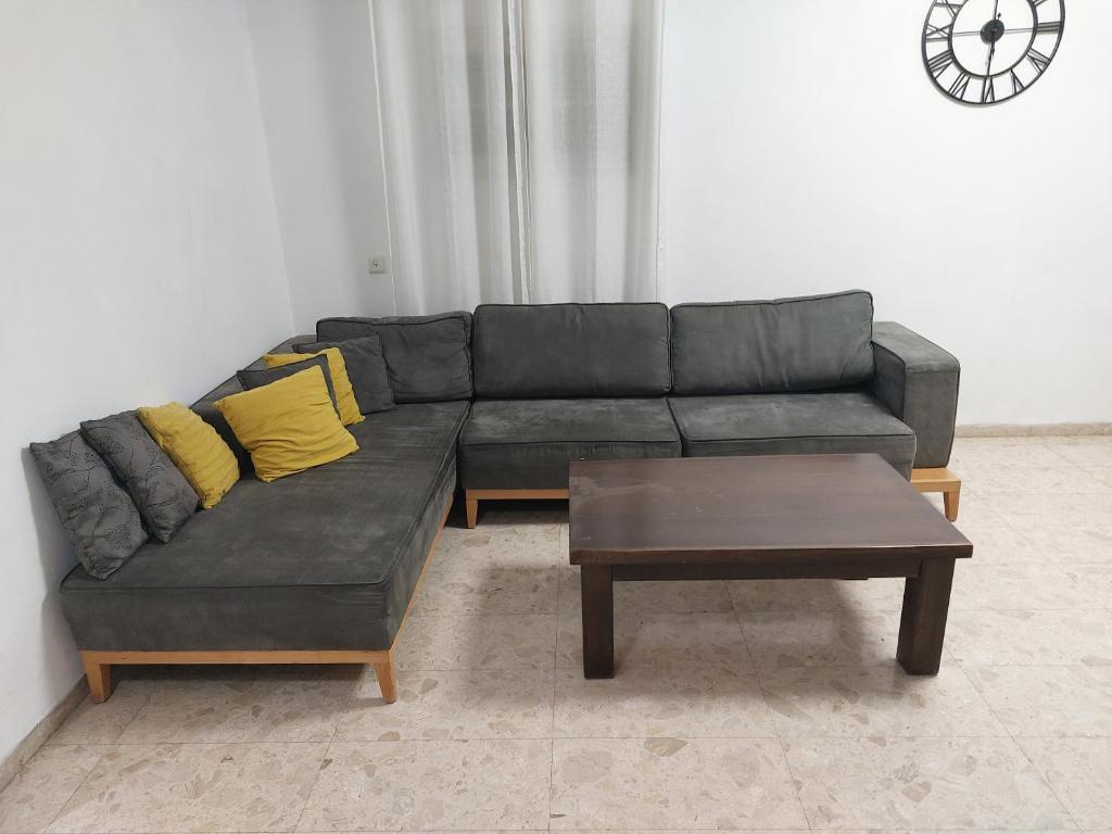 a black couch with yellow pillows and a coffee table at דירה בעמק in Bet Sheʼan